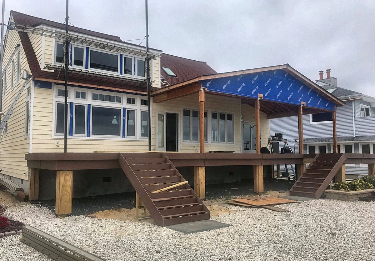 House wrapped with new windows, deck boards and stairs installed