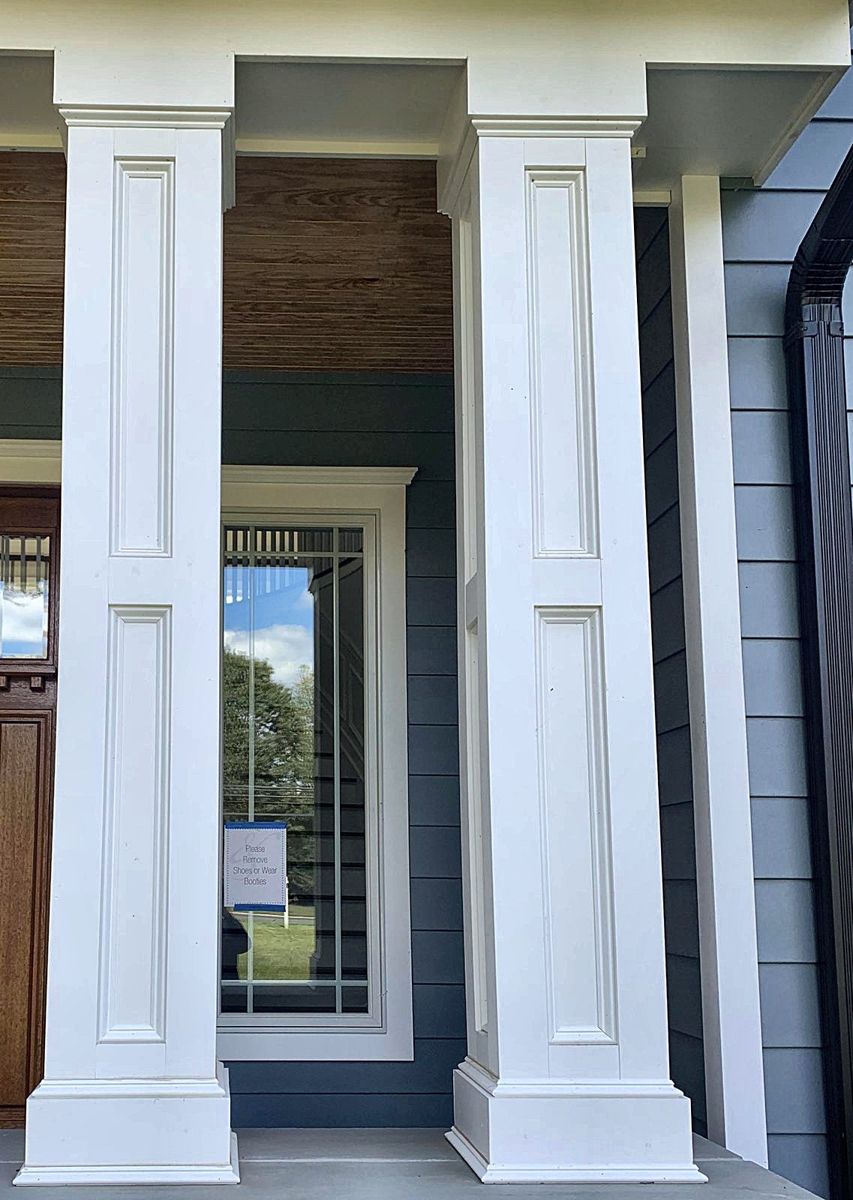 Pair of white paneled square columns on a stone porch