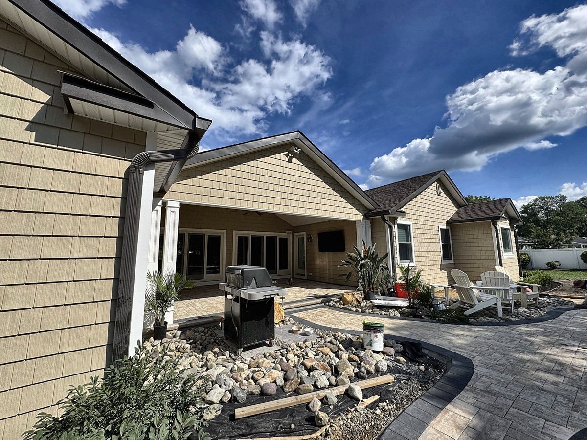 Covered patio with shingle siding and paver patio