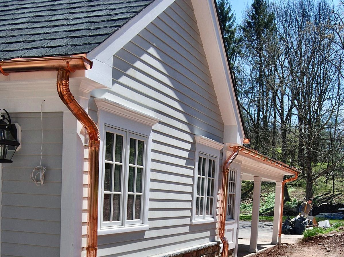 Clapboard addition with copper gutters, cased windows and a stone base