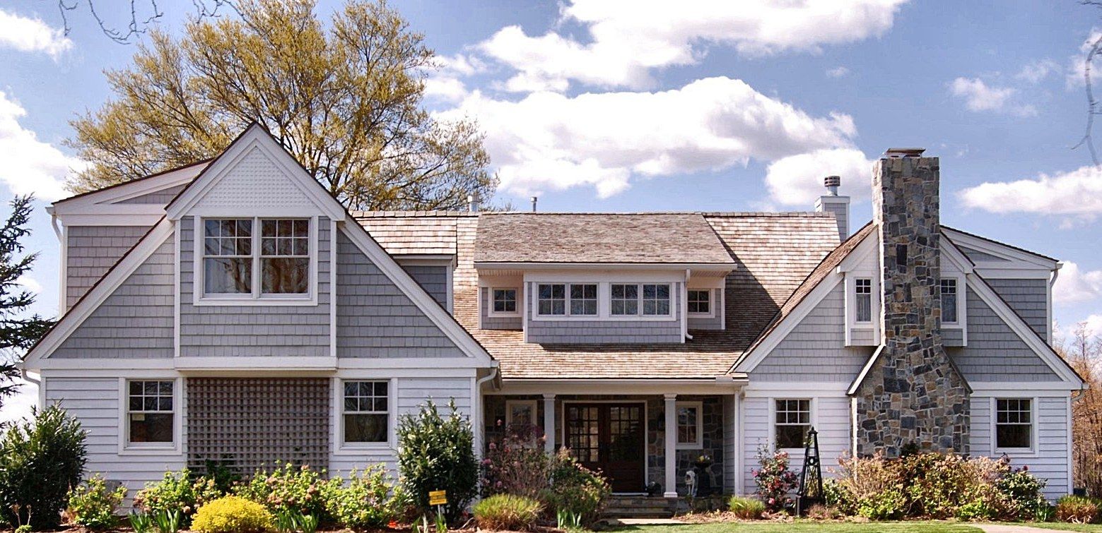 Shingle-style custom home in Rumson with a stone chimney and cedar roof